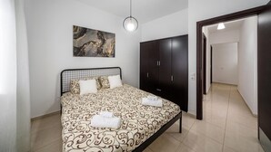Un dormitorio con cama, un armario, un cuadro en la pared y un pasillo.