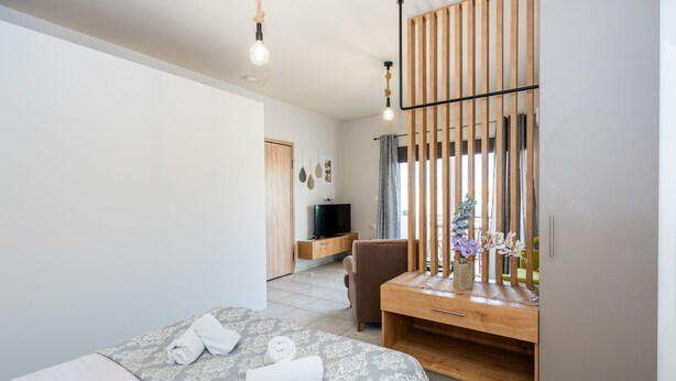 A modern hotel room with a bed, a wooden desk, a TV, and a chair. - George's House in City center (Iraklio)