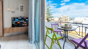 A balcony with a TV, colorful chairs, and a table. - George's House in City center (Iraklio)