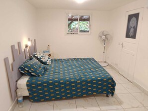 A bedroom with a bed, a window, a fan, and a door. - The house of Sainte Rose (Sainte-Rose)