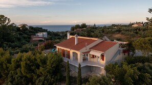 A coastal villa with a red-tiled roof, surrounded by dense greenery and overlooking the sea. - La Belle Villa - Family Retreat & Magnificent View (Zakinthos)