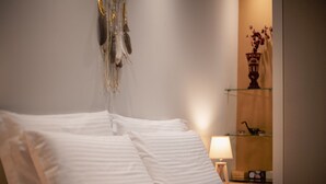 Ein ordentlich bezogenes Bett mit weißer Bettwäsche und einem dekorativen Wandbild darüber.