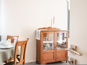A dining area with a wooden cabinet containing glassware and a white cloth on top. - Elegant City Apartment - 250m from Solomos Square (Zakinthos)