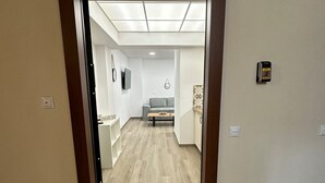 A hallway leading to a living area with a sofa and a TV. A 'HOME' mat is placed at the entrance. - Academy's Family Apartment by Athens Urban Retreat (Athina)