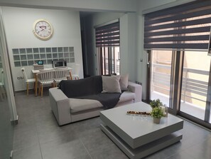 A modern living room with a sofa, coffee table, and a dining area with a table and chairs.