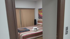 A hotel room with a bed, a flat-screen TV, a window with curtains, and a door. - Praxitelous Modern Suite by Athens Urban Retreat (Athina)