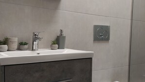A modern bathroom with a white sink, grey cabinets, and a toilet. - Praxitelous Modern Suite by Athens Urban Retreat (Athina)