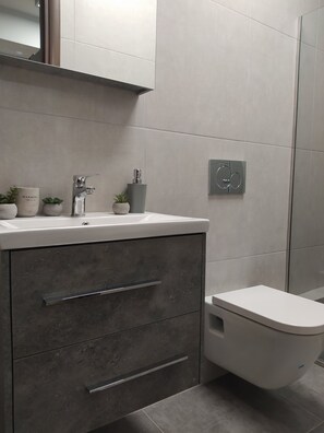 A modern bathroom with a white sink, grey cabinets, and a toilet. - Praxitelous Modern Suite by Athens Urban Retreat (Athina)