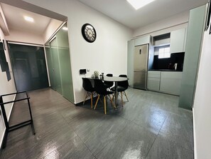 A modern kitchen with a built-in refrigerator and a dining area with a round table and chairs. - Ermou Superior Suite by Athens Urban Retreat (Athina)