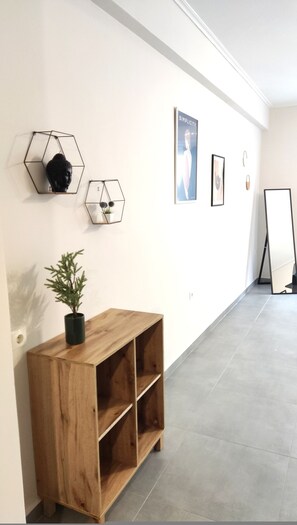 Ein Flur mit einem Holzkonsolentisch, Wandkunst in sechseckiger Form und einem Poster an der Wand.