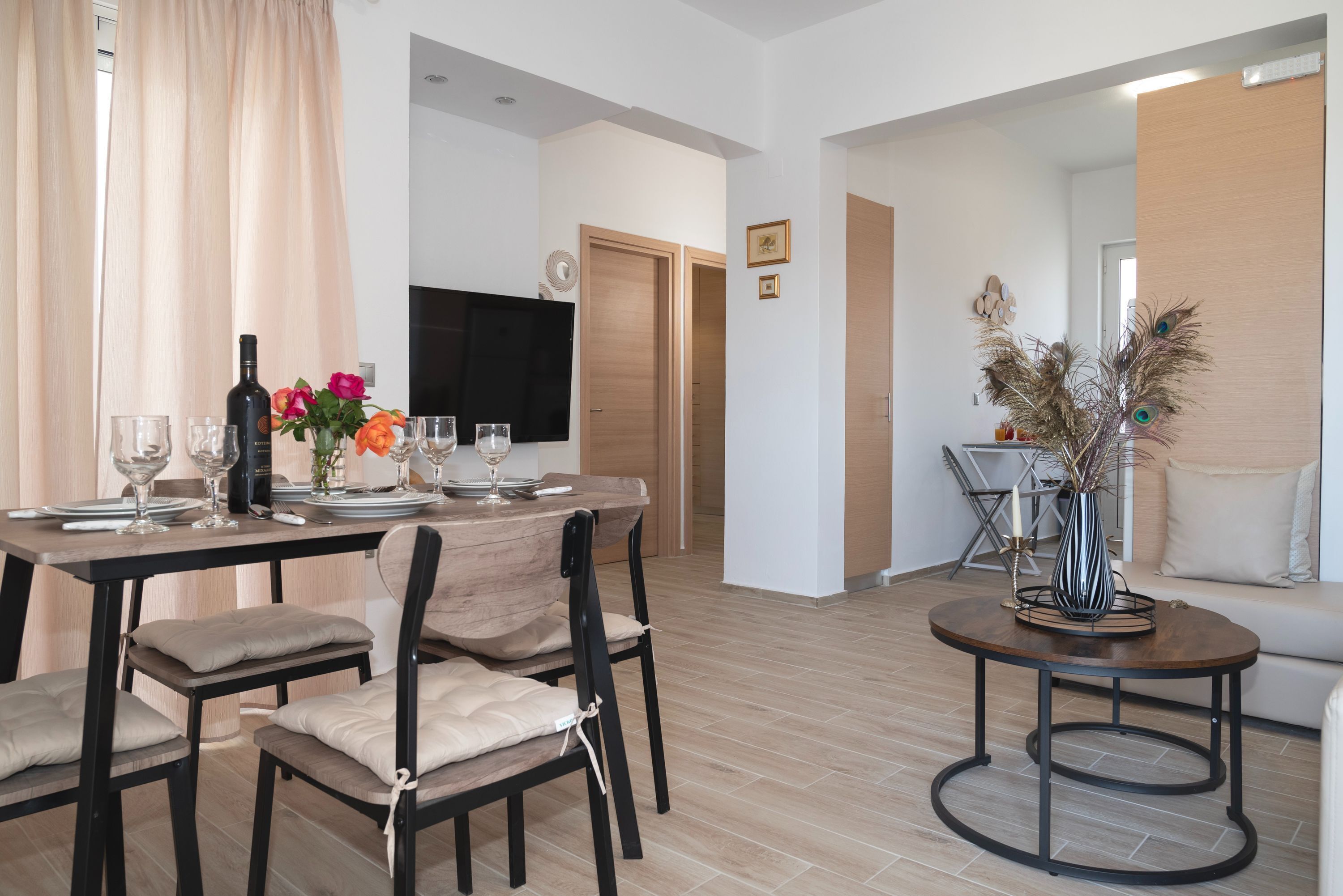 Ein Essbereich mit Holztisch, gedeckt für vier Personen, einer Couch und einer dekorativen Vase.