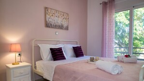 Um quarto com cama, mesa de cabeceira, luminária e janela com cortinas.