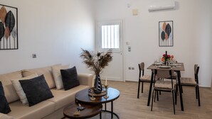 Sala de estar com sofá, mesa de centro e mesa de jantar posta para dois.