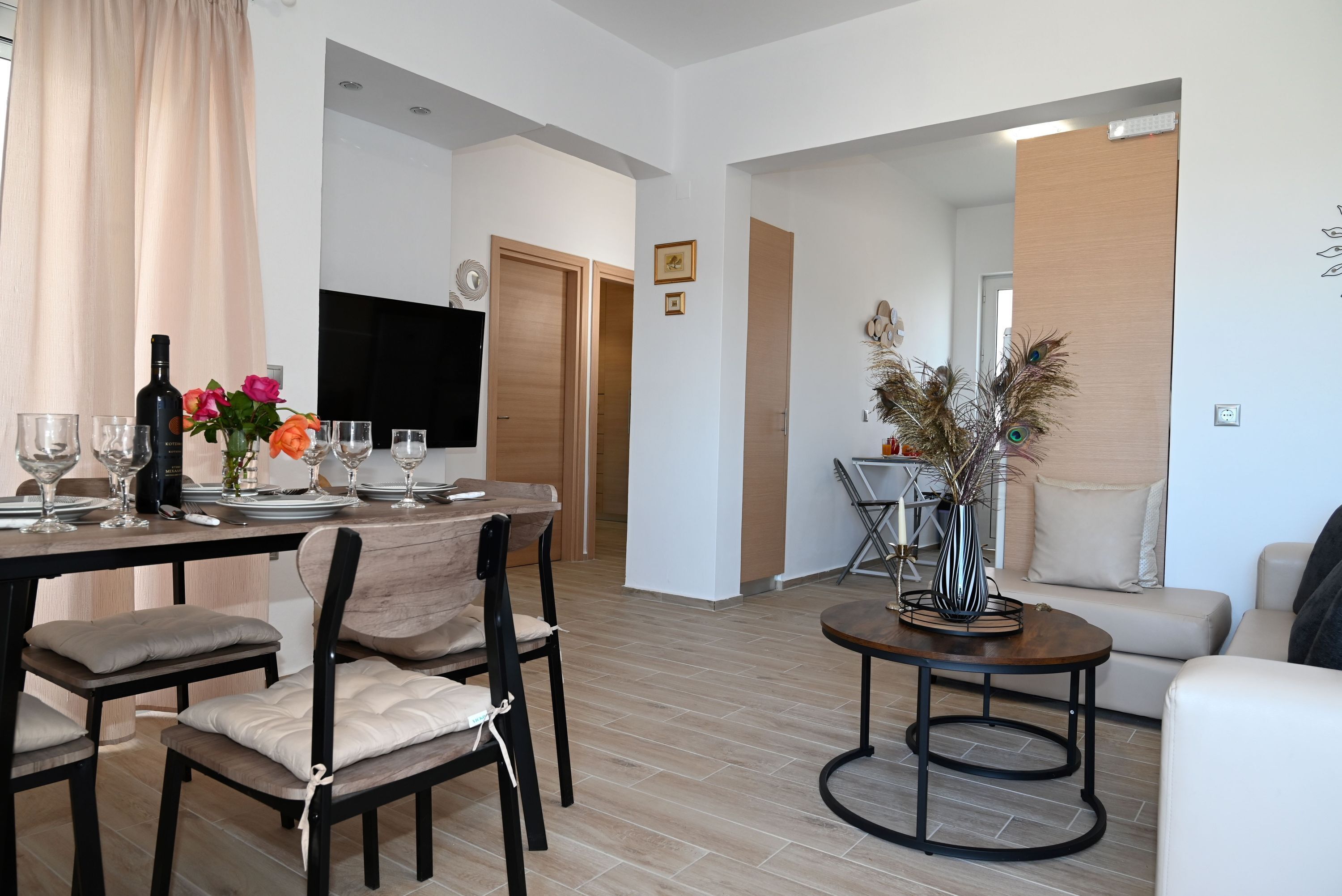 Ein modernes Wohnzimmer mit Essbereich, ausgestattet mit einem Holztisch für vier Personen, einer Couch und einem Couchtisch.