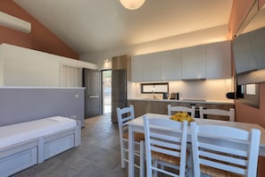 A modern kitchen with grey cabinets, a white dining table with chairs, and a built-in bench with storage drawers.