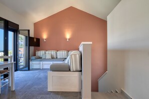 A modern interior with a high ceiling, a built-in seating area with cushions, and a staircase.
