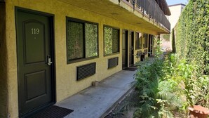 Un edificio con una puerta verde marcada '119', ventanas amplias y un balcón con barandillas de metal.
