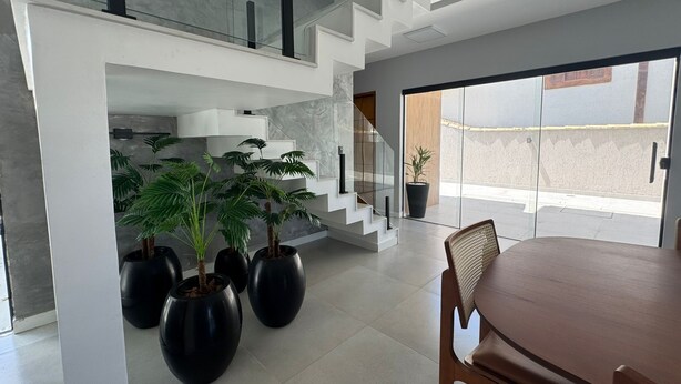 Un intérieur moderne comprenant un coin repas, un escalier et des plantes en pot.