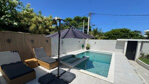 Une piscine avec des chaises longues et un espace abrité.
