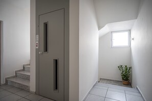 Eine saubere, moderne Treppe mit einer Tür, einem kleinen Fenster und einer Topfpflanze.