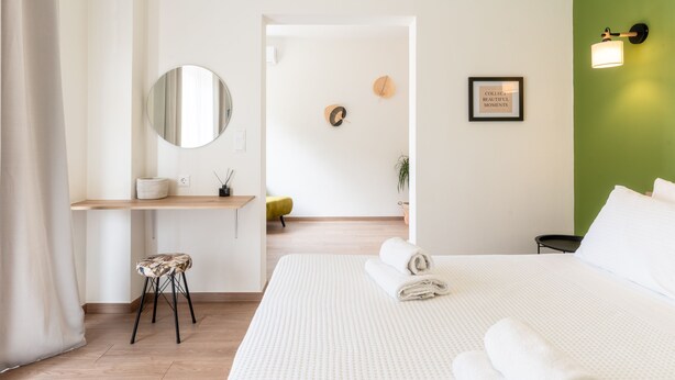 Habitación de hotel moderna con una cama grande, un escritorio, una silla y una pared verde de acento.
