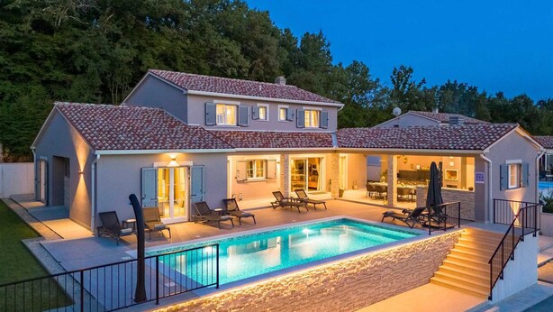 Ein zweistöckiges Haus mit Swimmingpool, Außenbereich mit Sitzgelegenheiten und einer überdachten Terrasse.