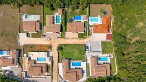 Eine Vogelperspektive auf ein Wohngebiet mit mehreren Häusern, die jeweils einen Swimmingpool und ein Ziegeldach haben.