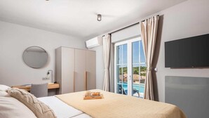 Ein Hotelzimmer mit einem Bett, einem Schreibtisch mit Stuhl, einem Kleiderschrank, einem Fernseher und einem Fenster mit Vorhängen.