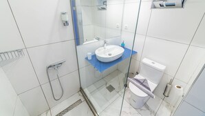 Et moderne badeværelse med en glasafskærmet brusebad, en hvid vask og et toilet.