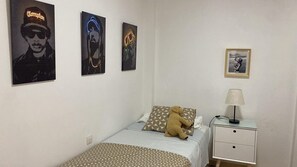 A bedroom with a bed, a nightstand, a lamp, and three posters on the wall. - Cozy house in Seville with patio, terrace and 3 bedrooms (Sevilla)