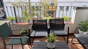 Una terraza con dos sillas negras, una mesa y plantas en macetas.