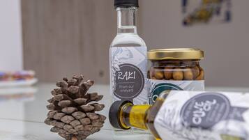 A bottle of Raki, a jar of nuts, and a pine cone on a table.