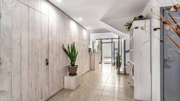 A modern hallway with wooden panel walls, a potted plant, and a tiled floor.