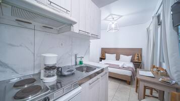 A compact kitchen with a stove, sink, and coffee maker. Adjacent to the kitchen is a small dining area with a table and chairs.