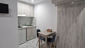 Une cuisine moderne avec un coin repas, dotée d’un sol en marbre, de meubles en bois et d’un four encastré.