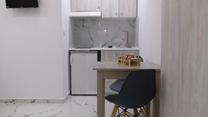 Une cuisine compacte avec des meubles blancs, un four à micro-ondes encastré et un petit réfrigérateur.