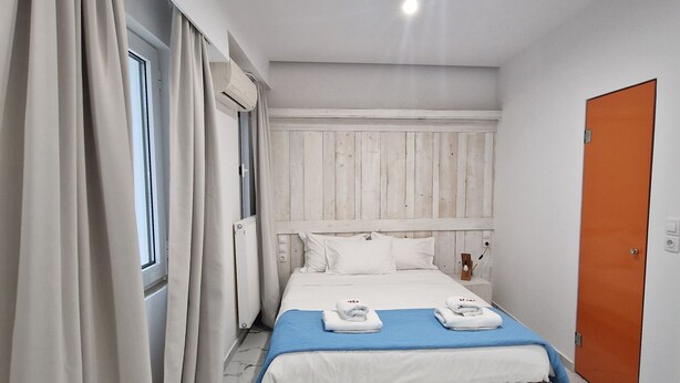 Une chambre à coucher avec un lit, des rideaux, un radiateur, une porte et un sol en marbre.