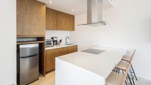 A modern kitchen with wooden cabinets, a stainless steel refrigerator, a built-in oven, a coffee maker, and a white island with bar stools. - Private pool, jungle view, AC and fast WI-Fi (Tulum)
