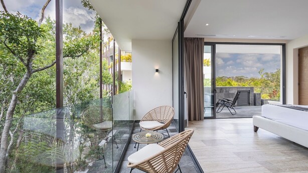 A modern balcony with glass railings, wicker furniture, and a view of greenery. - Private pool, jungle view, AC and fast WI-Fi (Tulum)