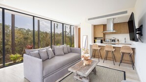 A modern living room with a grey sofa, a wooden coffee table, and a view of the outdoors. - Private pool, jungle view, AC and fast WI-Fi (Tulum)