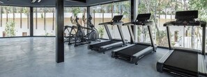A modern gym with treadmills, ellipticals, and a large window providing a view of the outdoors. - Cozy Studio in Tulum · Free Beach Shuttle (Tulum)