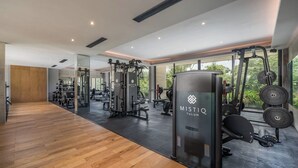 A modern gym with wooden flooring, exercise equipment, and large windows offering natural light. - Beautiful two bedroom for 6 guests (Tulum)