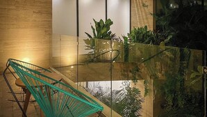 A modern interior with a glass railing, a green chair, and a variety of plants. - Beautiful two bedroom for 6 guests (Tulum)