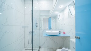 Et moderne badeværelse med en glasbrusekabine, en hvid vask og et toilet.