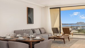 A modern living room with a dining area, a sofa, and a view of the sea. - Oceanview Escape • Fast Wi-Fi • AC • Chic Design (Cabo San Lucas)