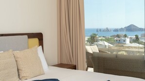 A hotel room with a bed, a nightstand, and a view of the sea and buildings. - Oceanview Escape • Fast Wi-Fi • AC • Chic Design (Cabo San Lucas)