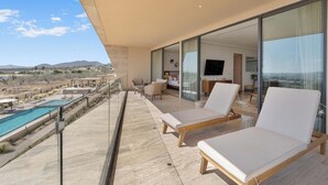 A balcony with a pool, two lounge chairs, and a view of the desert landscape. - Enjoy your perfect vacation in this 3 bd (Cabo San Lucas)