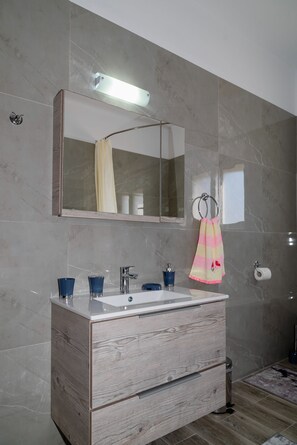 A modern bathroom with a marble wall, a wooden vanity, a mirror, and a towel ring. - Serenity Luxury Villa in Paradisi Rhodes (Paradisi)