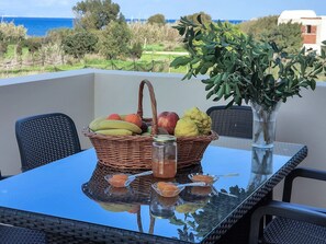 A table with a wicker basket containing fruits, a glass jar, and a vase with a plant. - Serenity Luxury Villa in Paradisi Rhodes (Paradisi)
