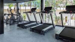 Ein Fitnessstudio mit Laufbändern, Crosstrainern und stationären Fahrrädern.